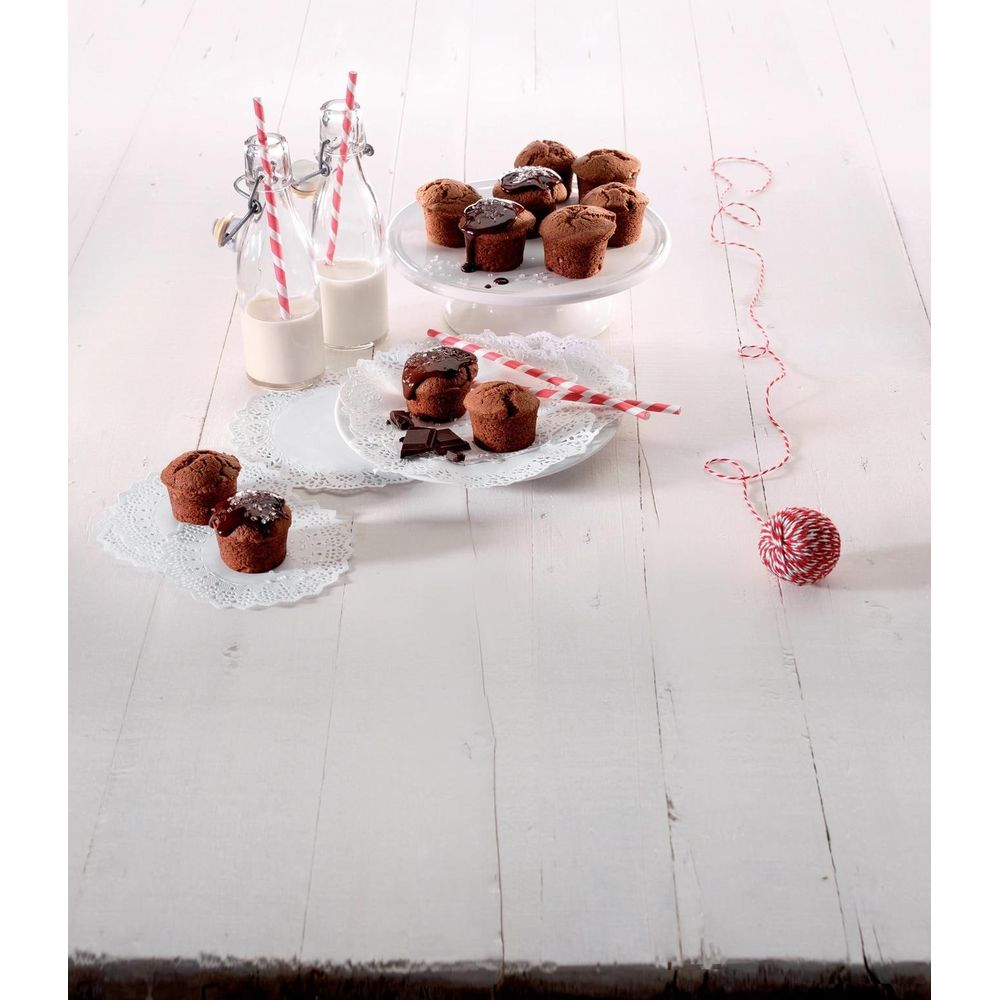 Muffins au chocolat avec glaçage au chocolat et lait en bouteilles sur table en bois blanc.