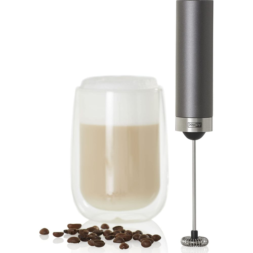 Mousseur à lait à côté d'un verre de café et de grains.