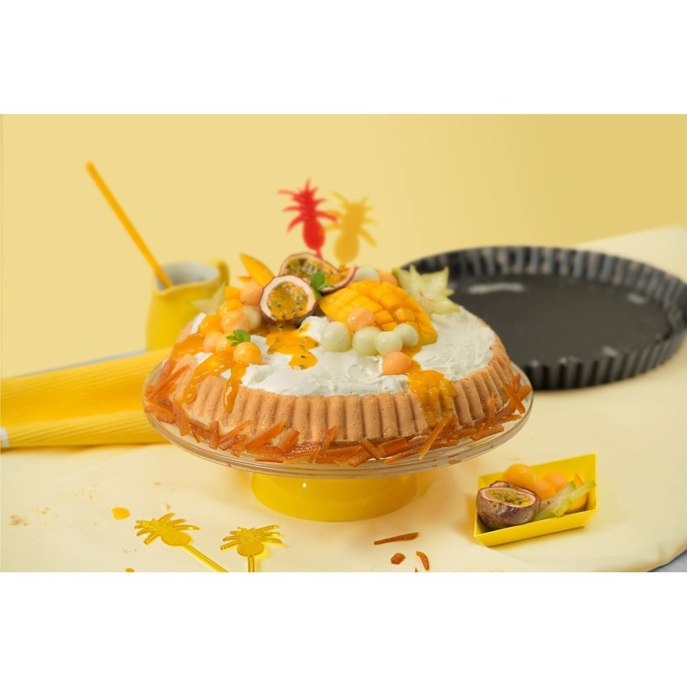 Eine runde Torte mit Schlagsahne, Mango, Passionsfrucht und Melonenbällchen.