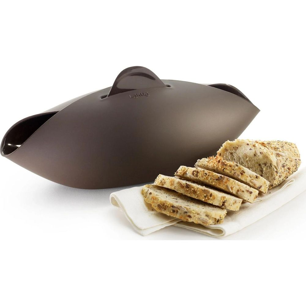 Brauner Brotkasten mit geschnittenem Körnerbrot auf weißem Tuch.