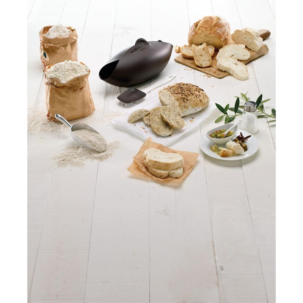 Brotbackutensilien und Brote auf Holztisch, zwei Mehlsäcke, Schaufel, Brotbackform, Brotlaibe und Scheiben.