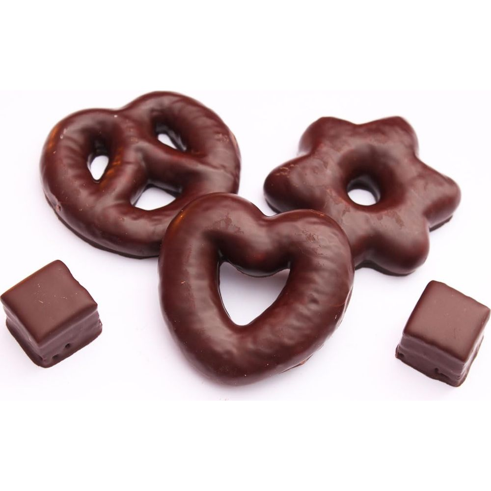 Drei Schokoladenlebkuchen in Herz-, Stern- und Brezelform, zwei kleine Würfel.