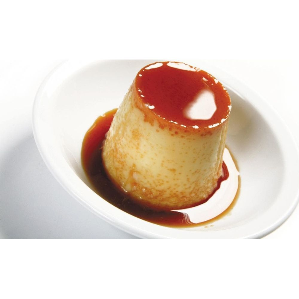 Ein Karamellpudding-Dessert in einer weißen ovalen Schale mit Karamellsauce.