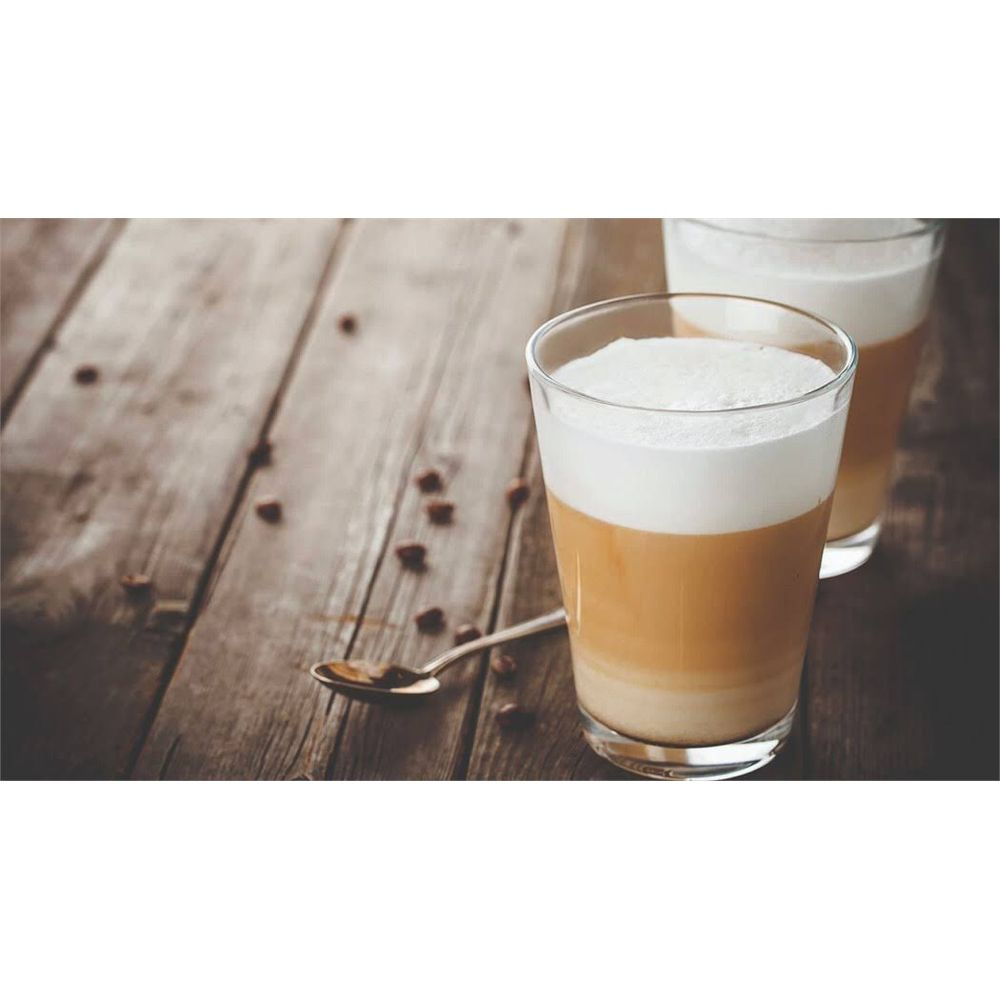 Deux verres de café en couches avec de la mousse sur une table en bois avec des grains de café éparpillés.