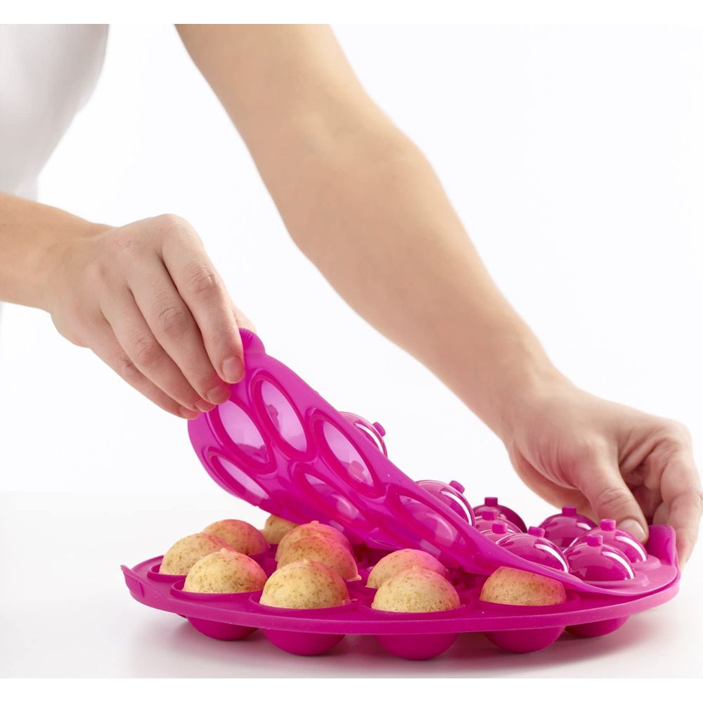 Eine Person hebt eine rosa Silikonform mit kleinen Küchlein heraus.