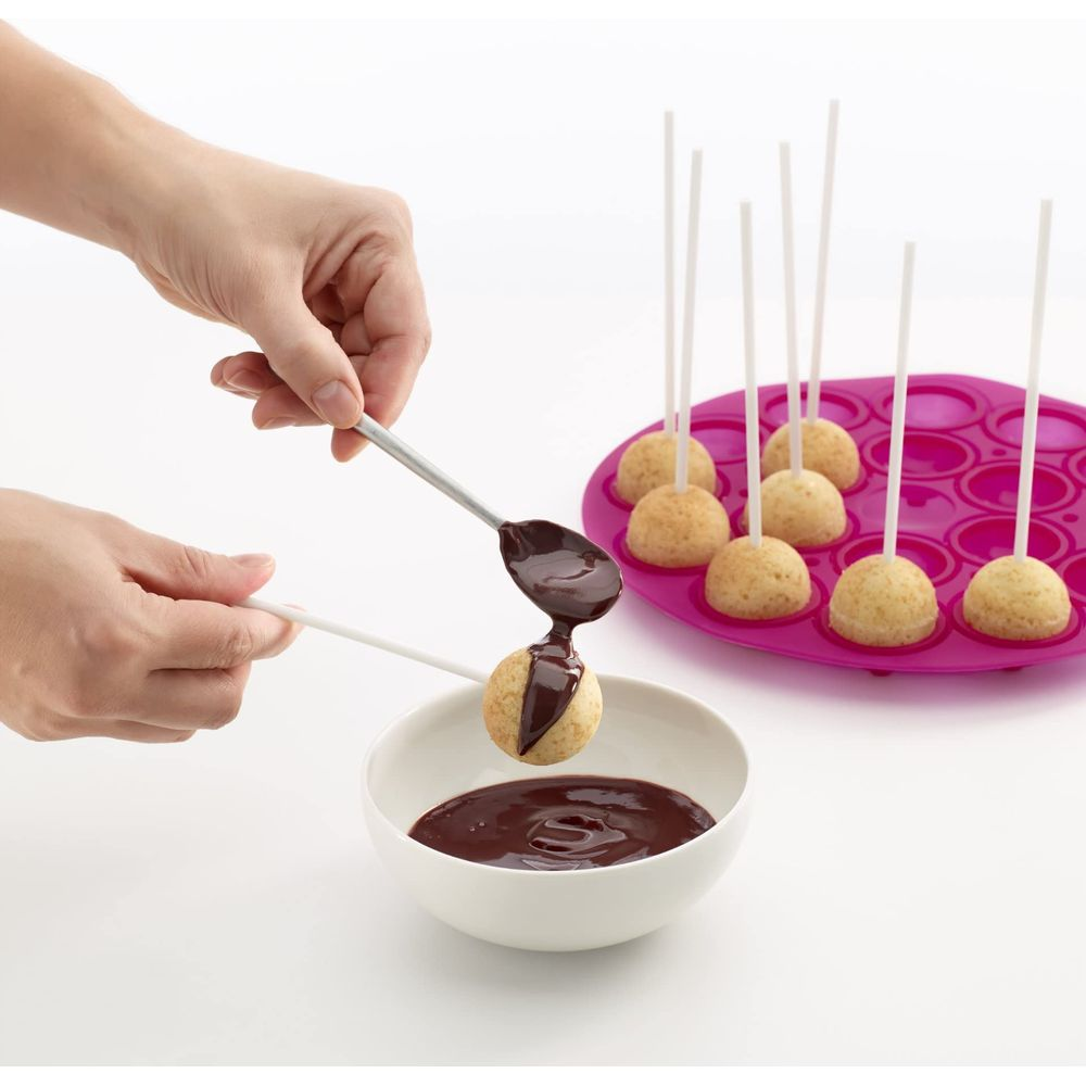 Hände glasieren Cake Pops mit Schokolade aus einem Löffel.