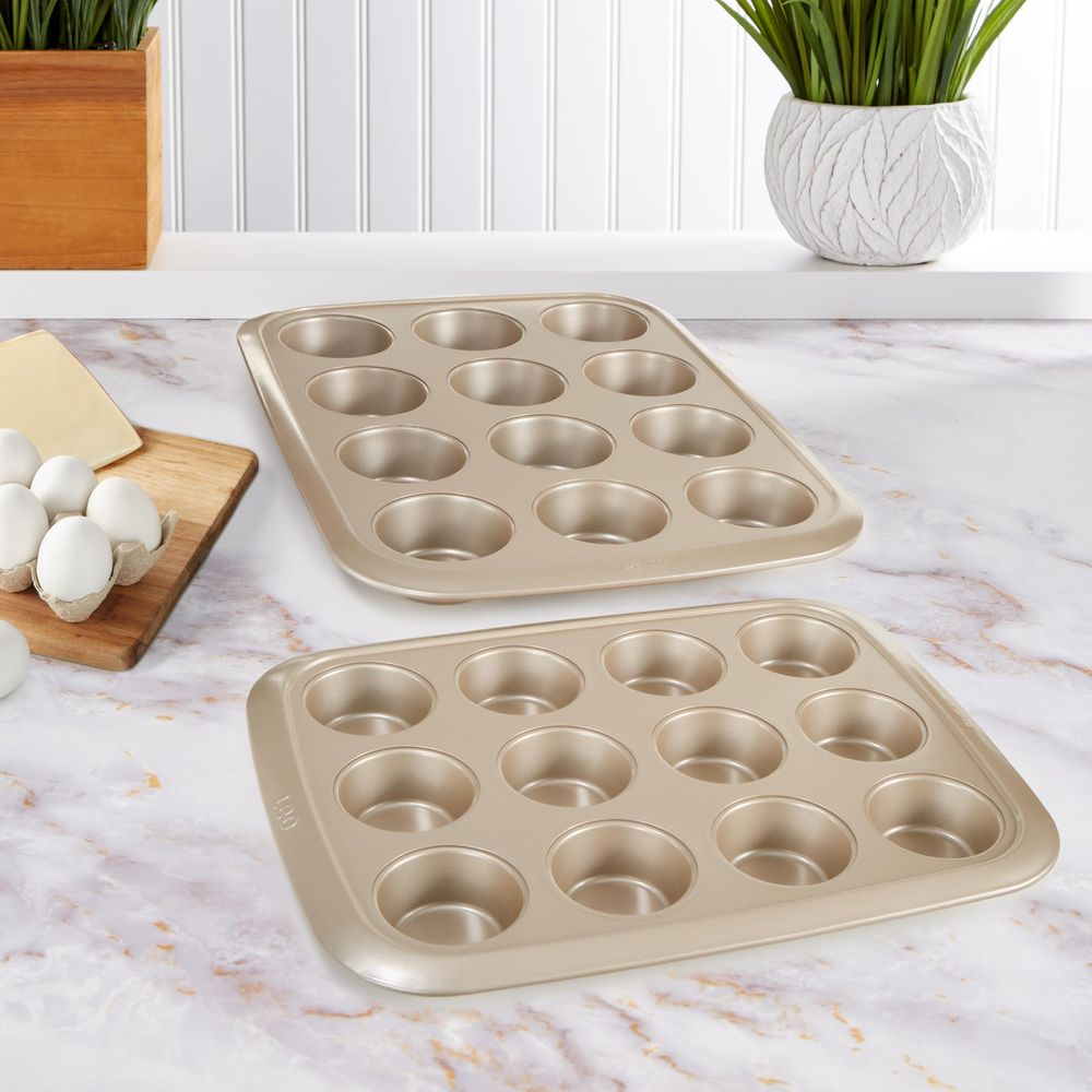 Zwei goldene Muffinbleche mit Eiern und Käse auf einer Marmorarbeitsplatte.