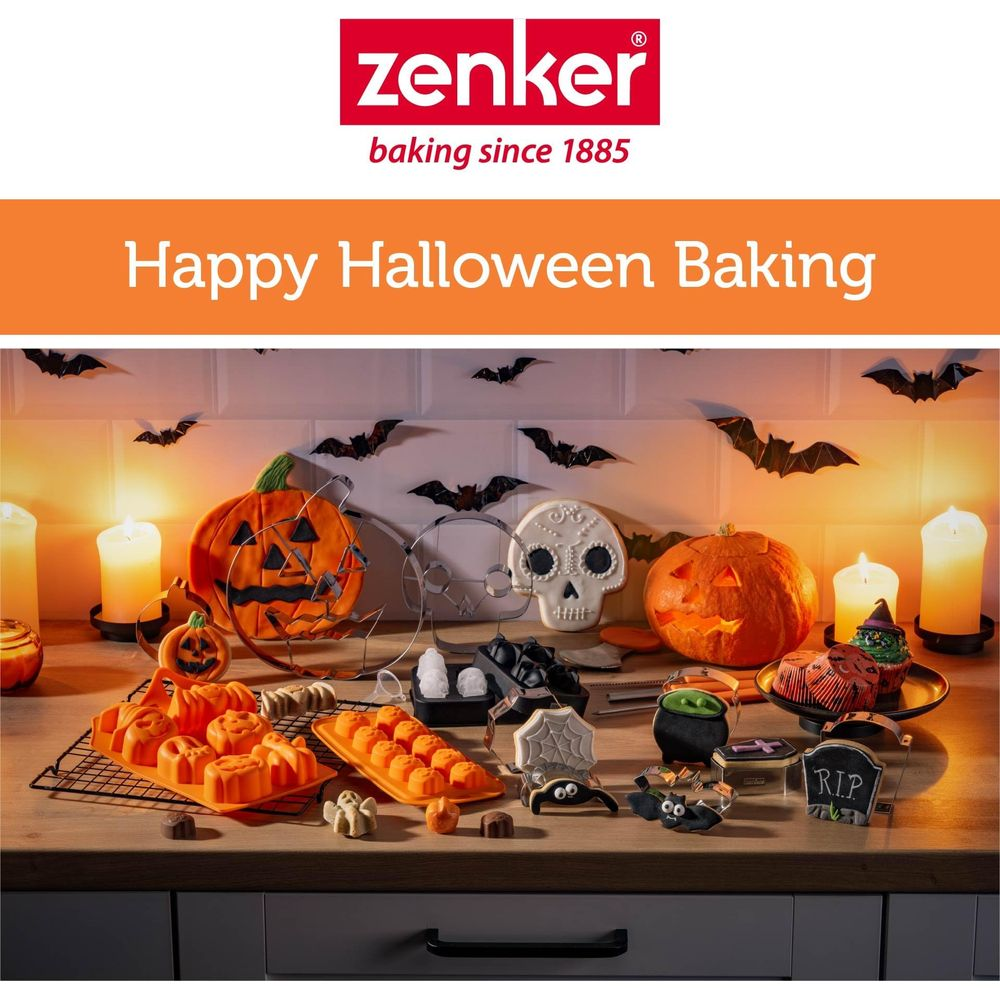 Halloween-Backauslage mit Kürbissen, Totenkopf-Keks, Kessel, Kerzen und Fledermausdekorationen.