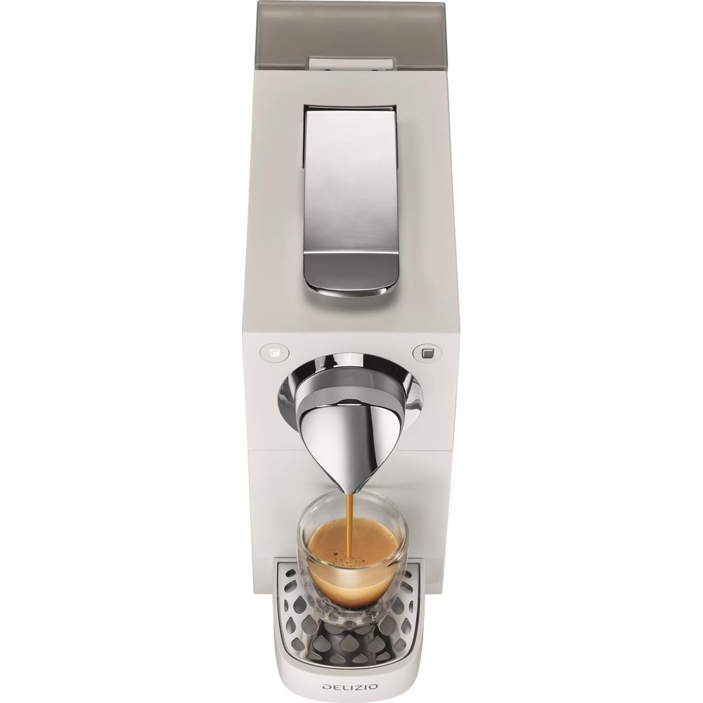 Eine weiße Kaffeemaschine brüht Espresso in ein Glas, das auf einem Gitter steht.
