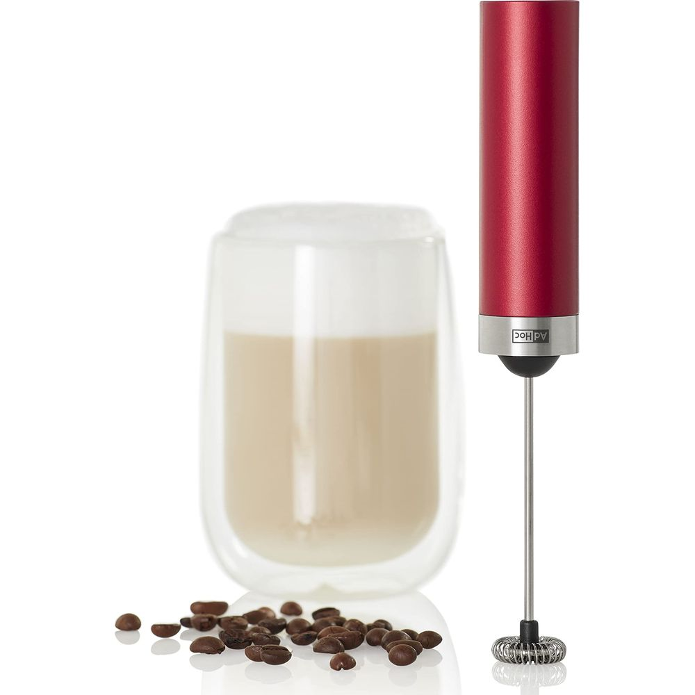 Un mousseur rouge à côté d'un verre de café au lait et de grains de café sur fond blanc.