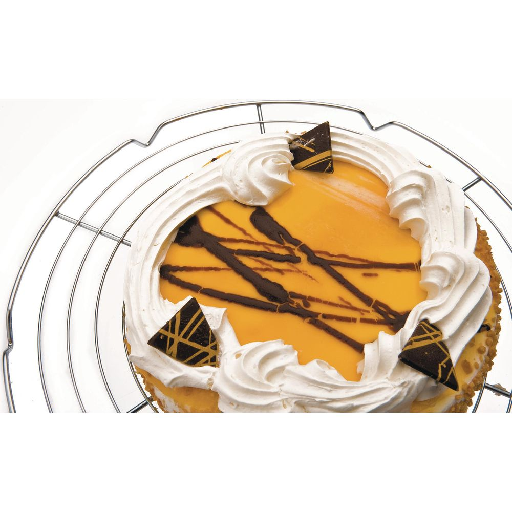 Un dolce rotondo con una parte superiore gialla, bordo di panna montata bianca, gocce di cioccolato fondente e tre triangoli di cioccolato.