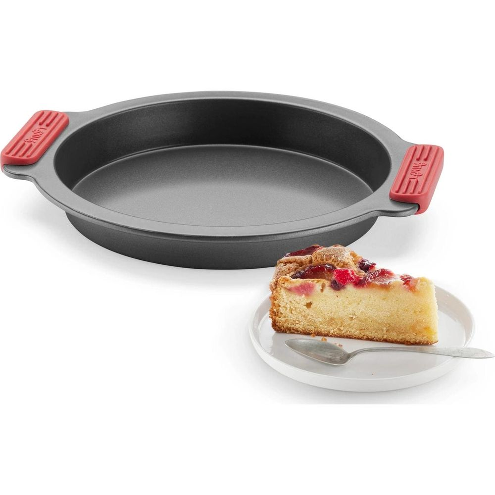 Un moule à gâteau rond avec des poignées rouges à côté d'une part de gâteau sur une assiette.