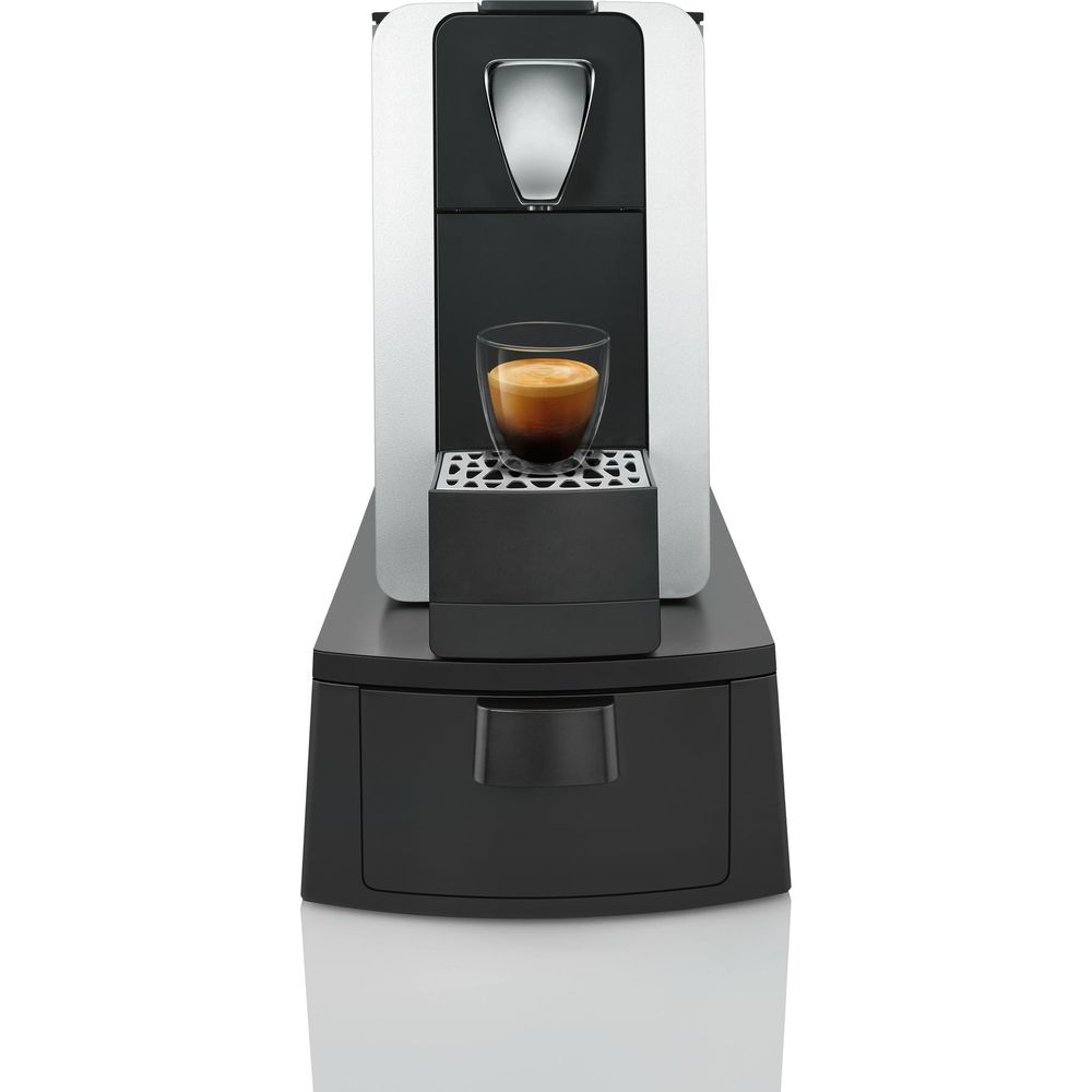 Eine silberne und schwarze Kaffeemaschine mit einem Glas Espresso.