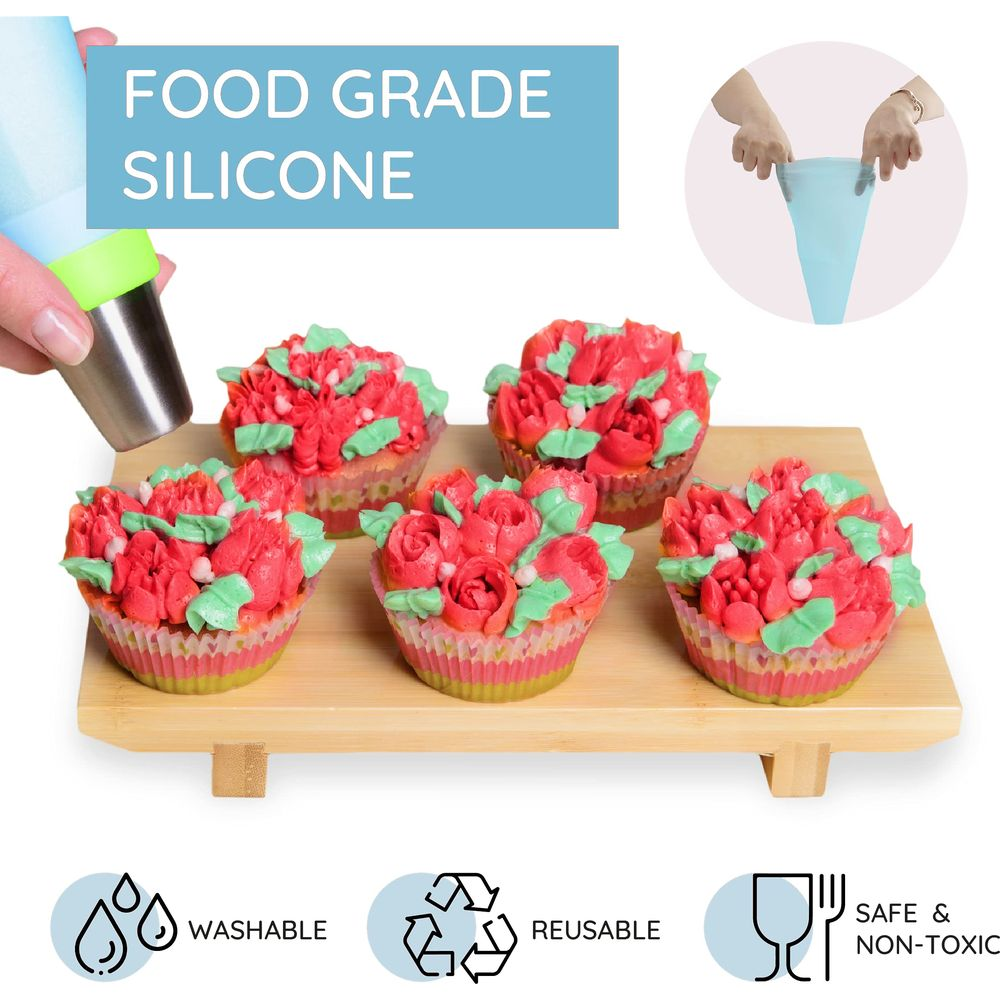 Cinq cupcakes décorés de fleurs en glaçage rouge et vert sur planche en bois.
