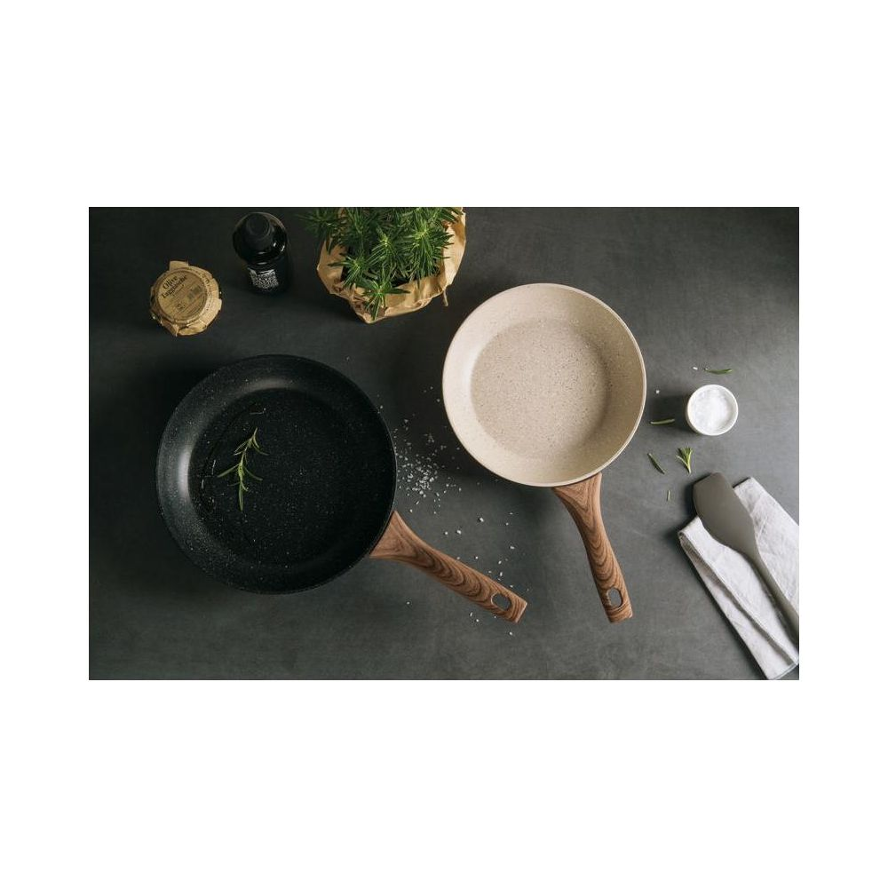 Deux poêles avec manches en bois, herbes et sel sur fond sombre.
