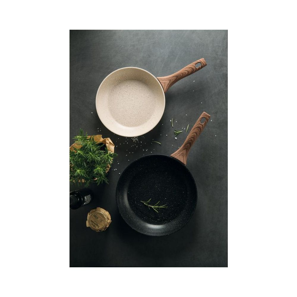 Deux poêles avec manches en bois, une claire et une foncée, avec des herbes et du sel.