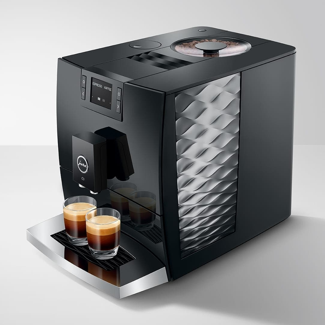 Macchina da caffè nera con due bicchieri da espresso pieni di caffè.
