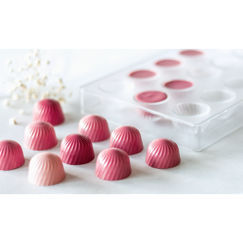 Chocolats roses disposés dans un bol et dans un moule.