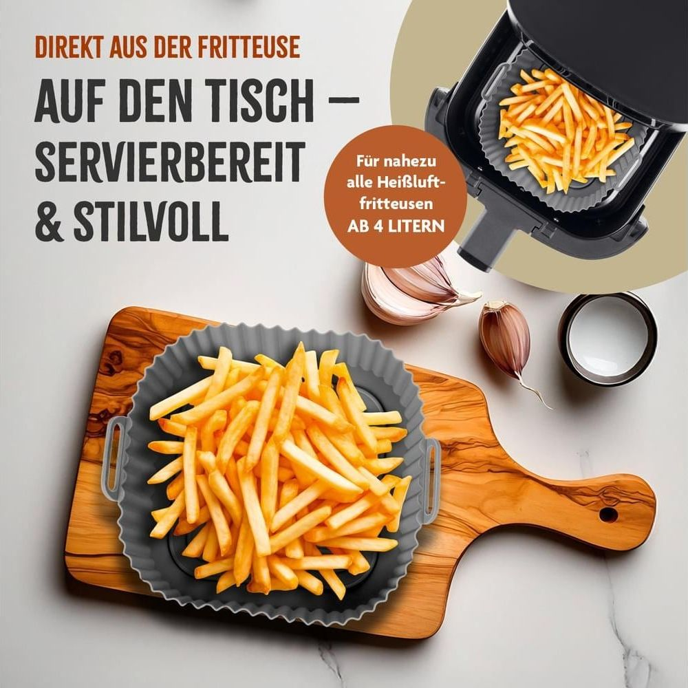 Pommes frites in einer grauen Silikonform auf einem Holzbrett neben Knoblauch und einer Schüssel.