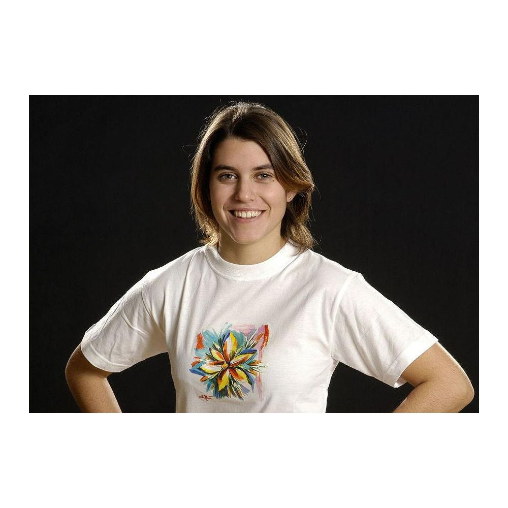 Une femme aux cheveux bruns porte un t-shirt blanc avec un motif floral coloré.