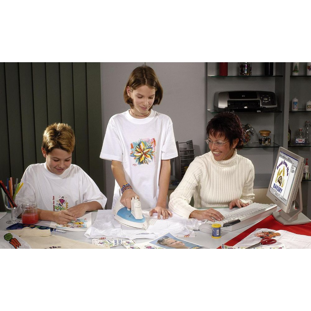 Trois personnes repassent des t-shirts et travaillent sur un ordinateur.