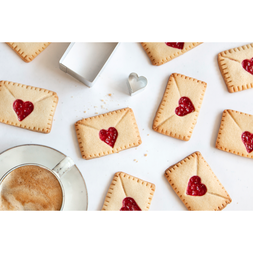 Biscuits en forme d'enveloppe avec cœurs de confiture, café et emporte-pièces.