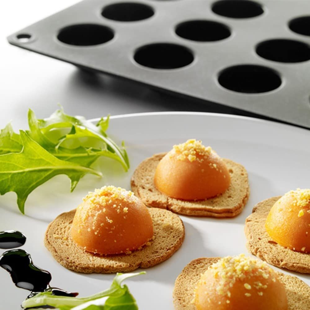 Orangefarbene Bällchen auf Crackern mit Salat und dunkler Soße.