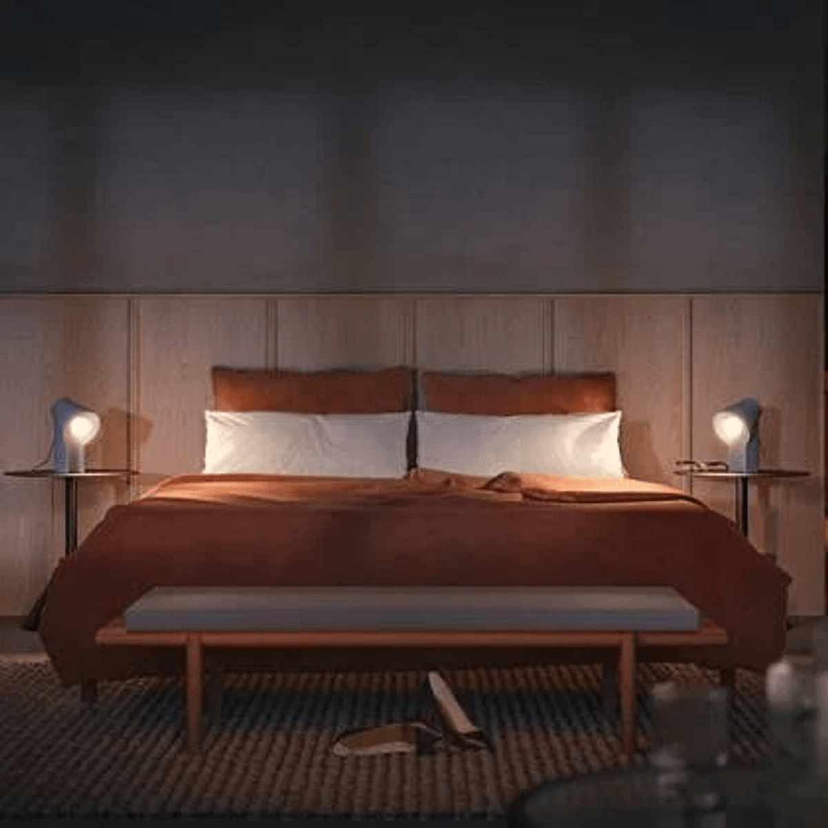 Un dormitorio moderno con cama grande, manta naranja y mesas auxiliares con lámparas.