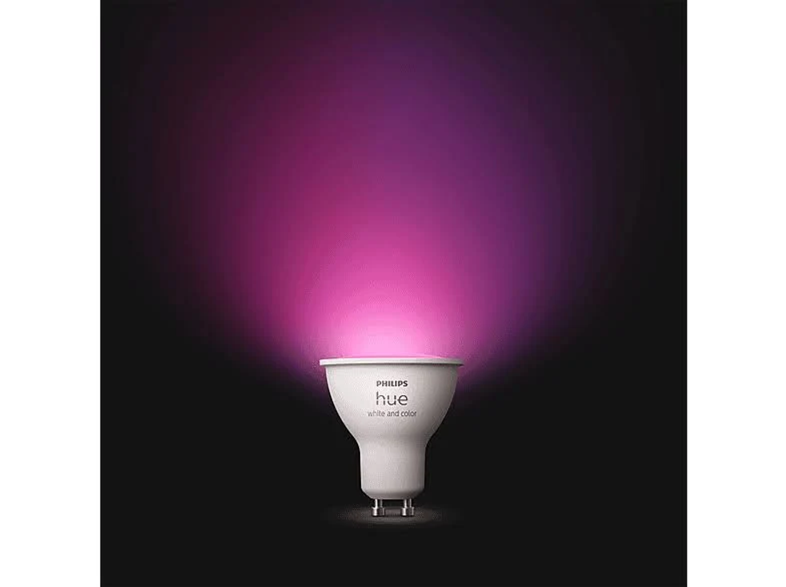 Eine weiße Philips Hue Glühbirne strahlt violettes Licht gegen einen dunklen Hintergrund.