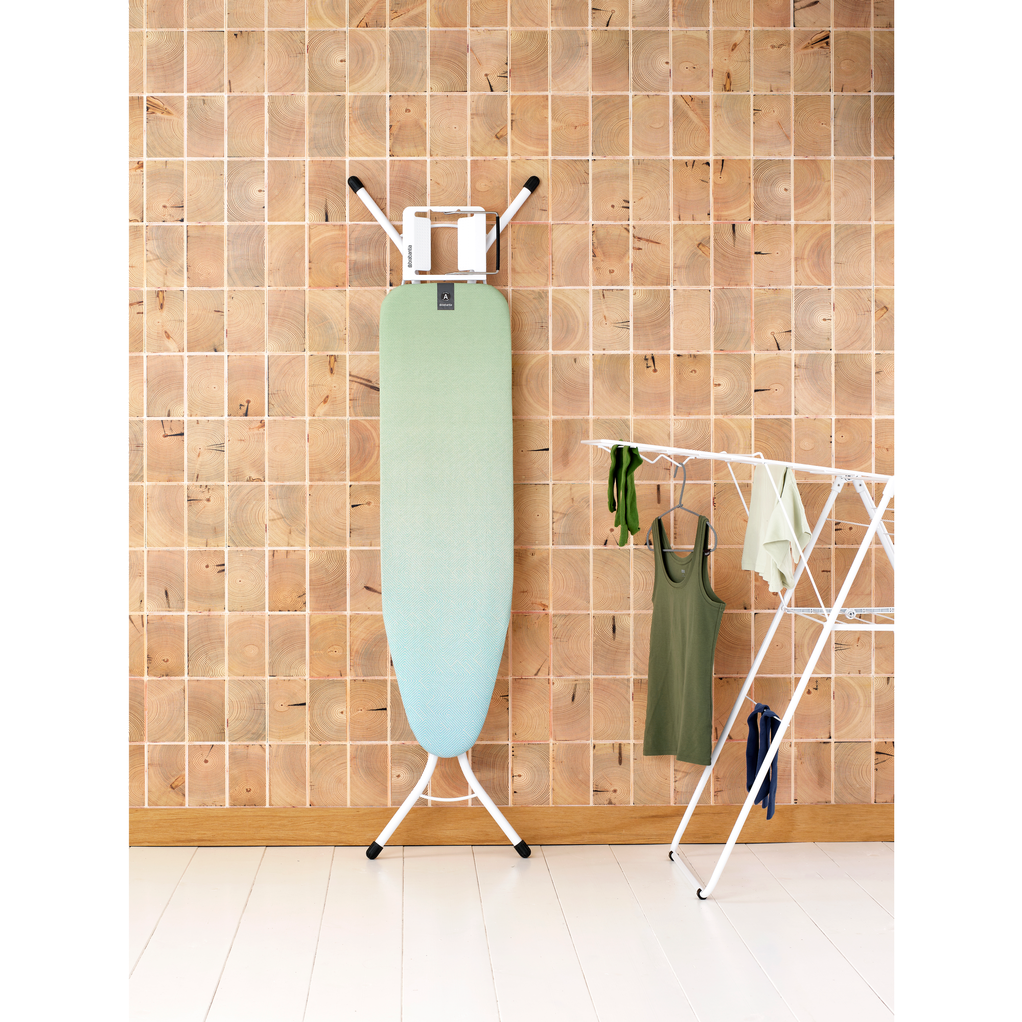 Une planche à repasser et un étendoir à linge devant un mur en bois.