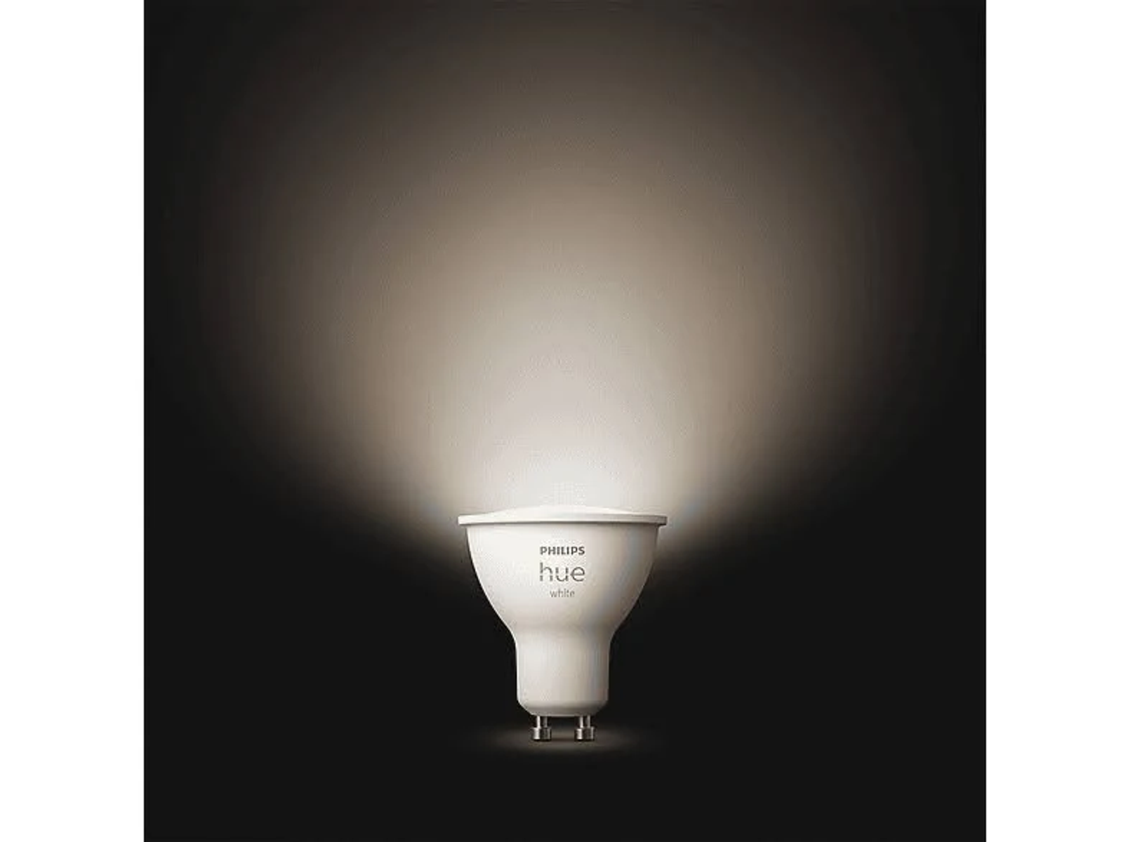 Eine weiße Philips Hue-Smart-Glühbirne leuchtet hell vor einem dunklen, texturierten Hintergrund.