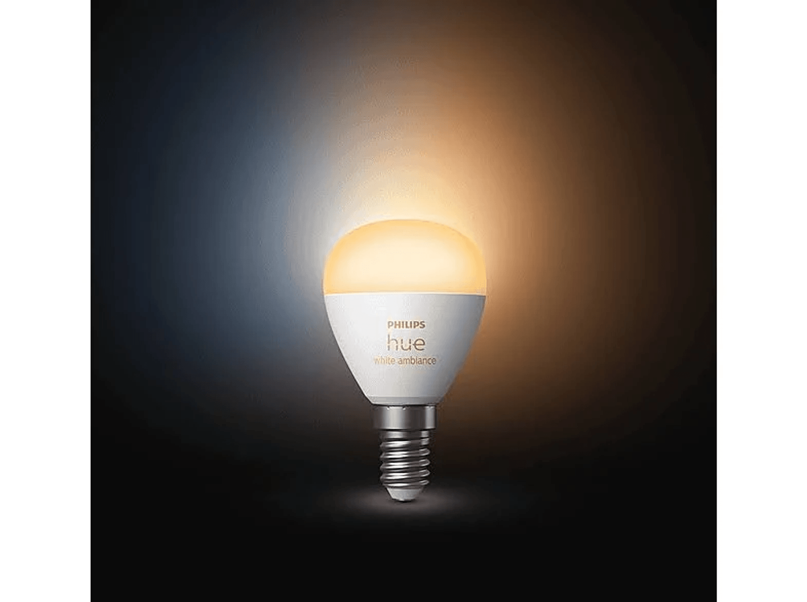 Eine weiße Philips Hue Glühbirne leuchtet warmes Licht auf dunklem Grund.
