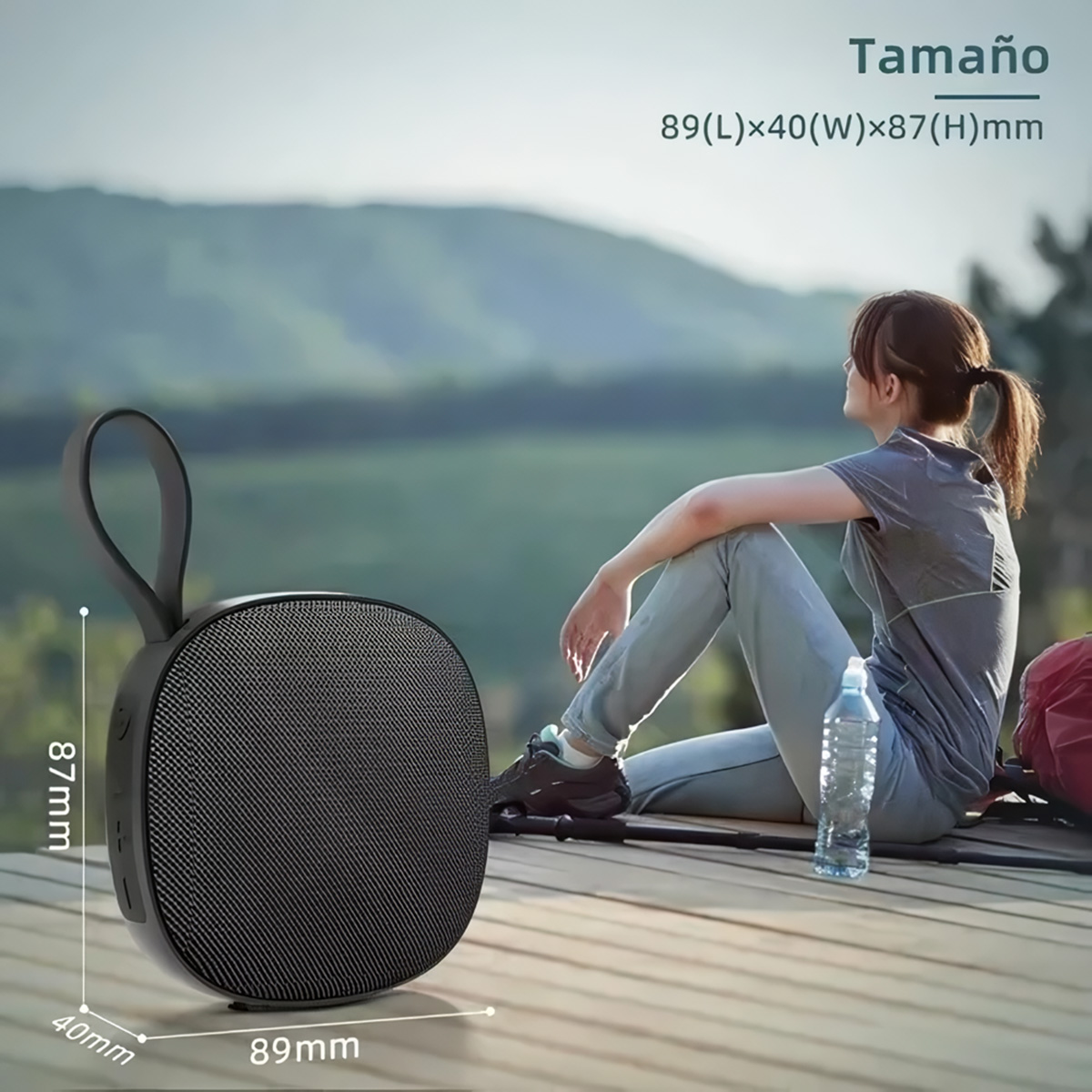 Altavoz negro con asa, medidas 89x40x87mm, en tarima de madera con fondo natural.