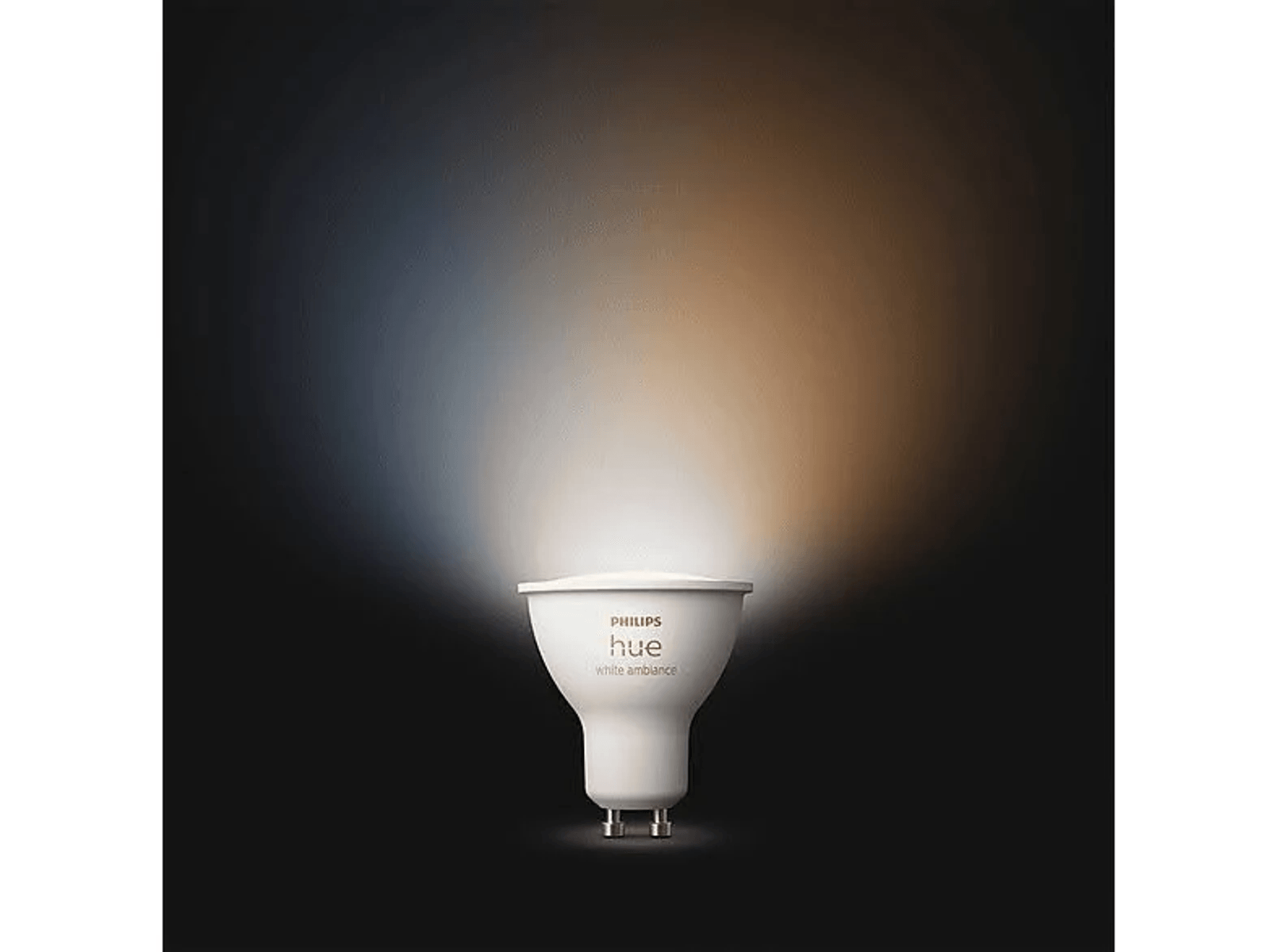 Eine weiße Philips Hue Glühbirne leuchtet mit kaltem und warmem Licht auf dunklem Grund.