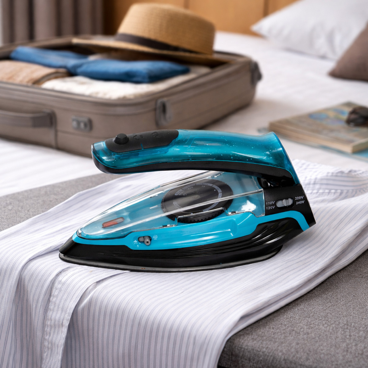 Una plancha de viaje azul descansa sobre una camisa a rayas. Maleta y sombrero al fondo.