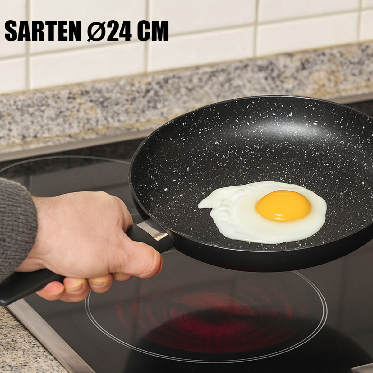 Una mano sostiene una sartén con un huevo frito, sobre una placa de cocina.
