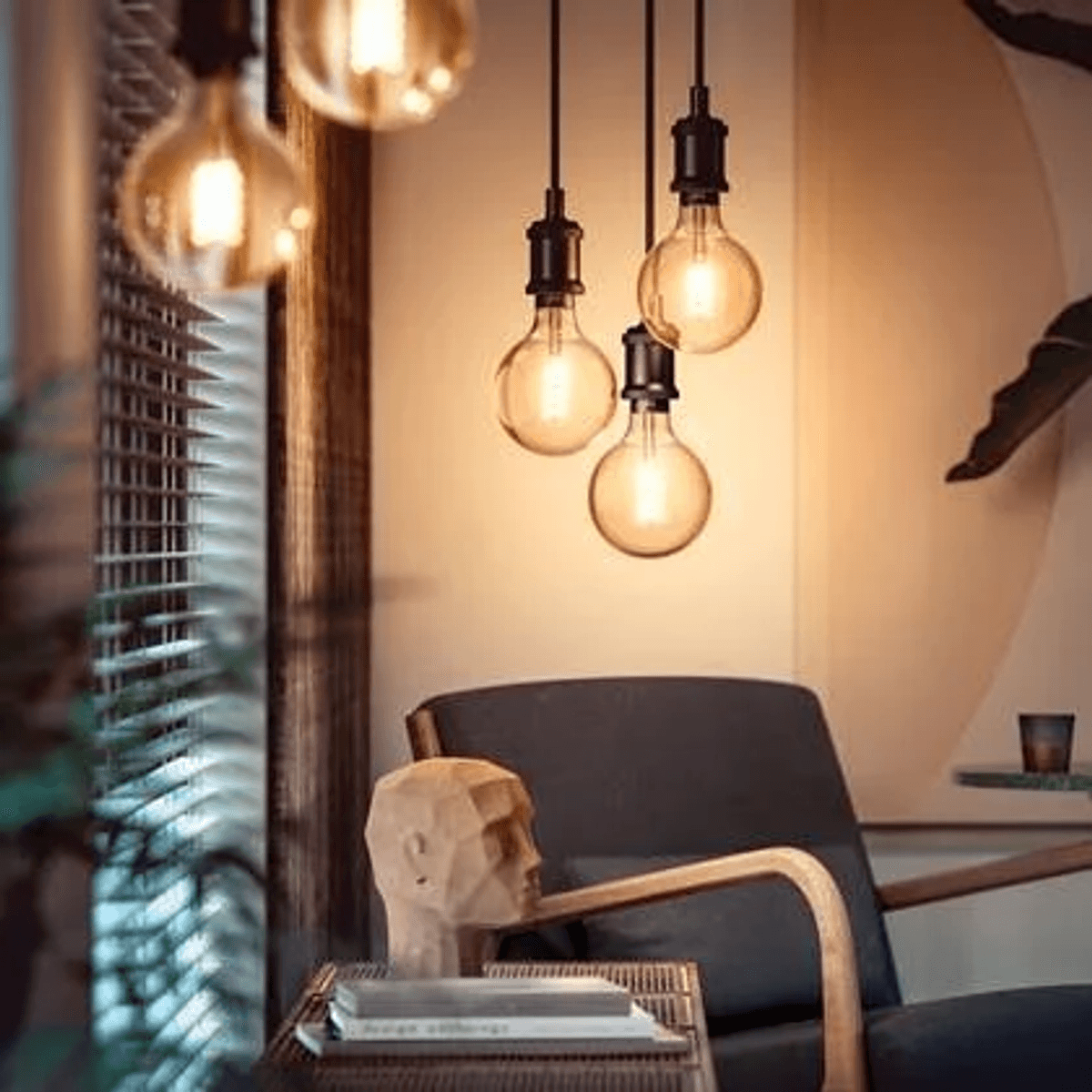 Ein Sessel mit Holzkopfskulptur und Hängelampen im Hintergrund.