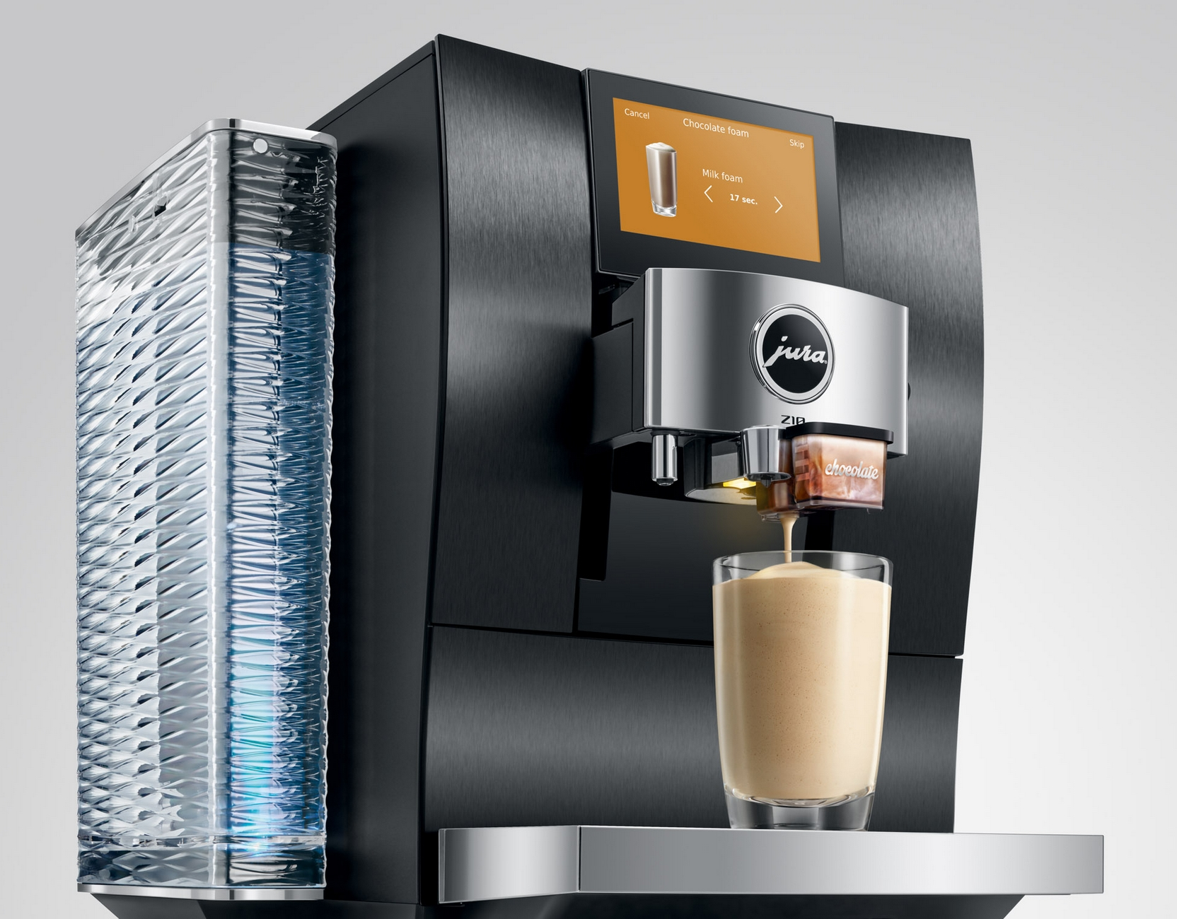 Una macchina da caffè nera con serbatoio dell'acqua in vetro che versa liquido schiumoso in un bicchiere.