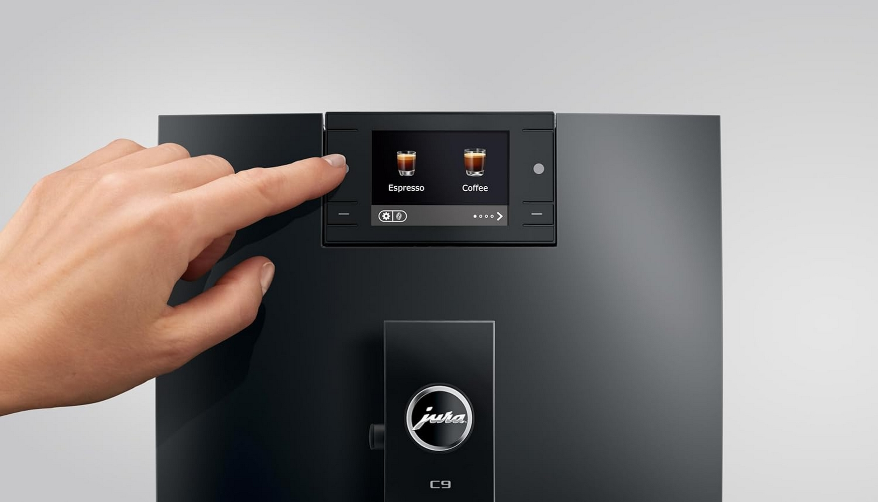 Una mano tocca lo schermo di una macchina da caffè che mostra le opzioni Espresso e Caffè.
