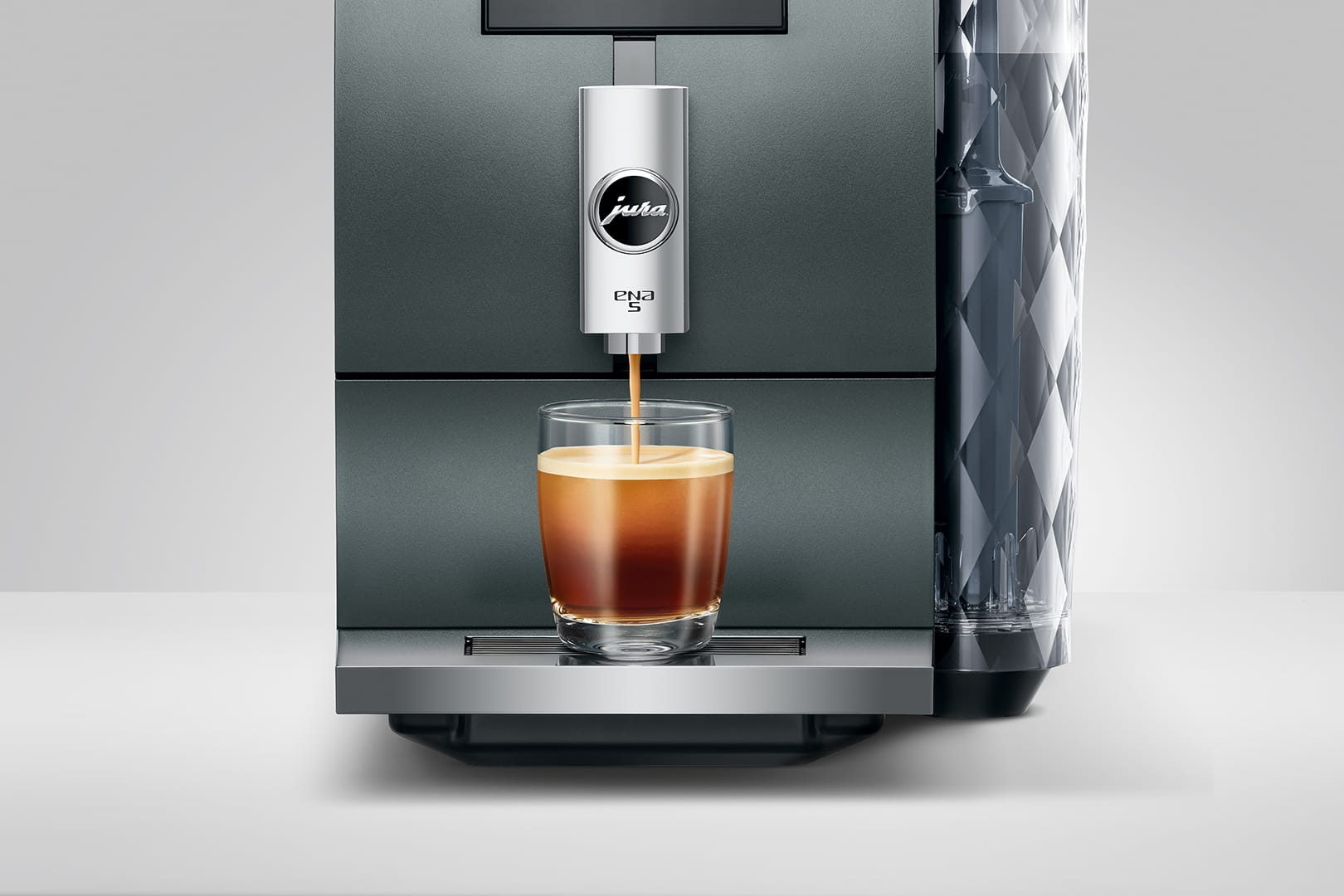 Kaffeemaschine brüht Espresso in ein Glas. Jura Ena S Logo.