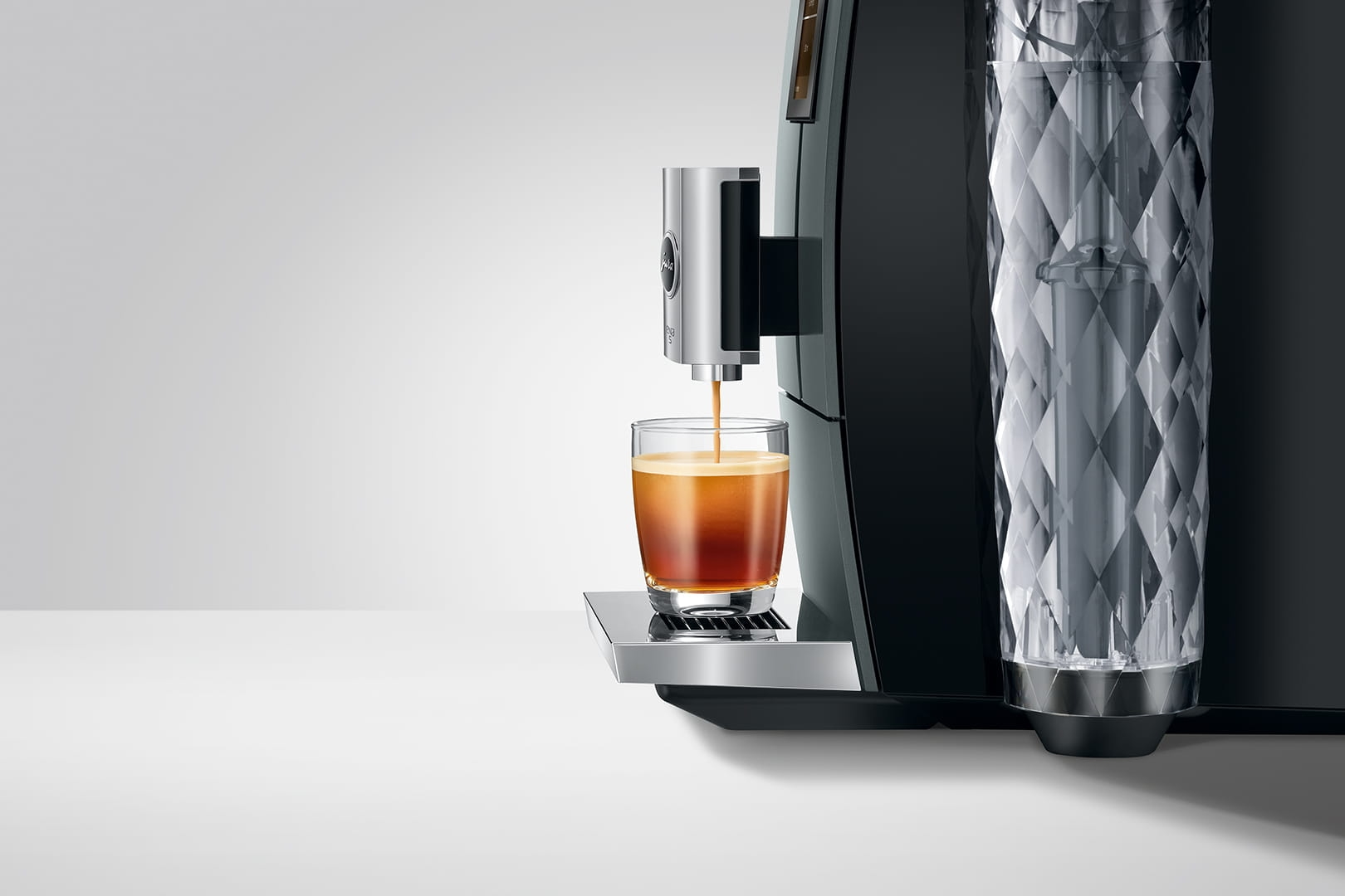 Una macchina da caffè prepara il caffè in un bicchiere. Un serbatoio dell'acqua è accanto.