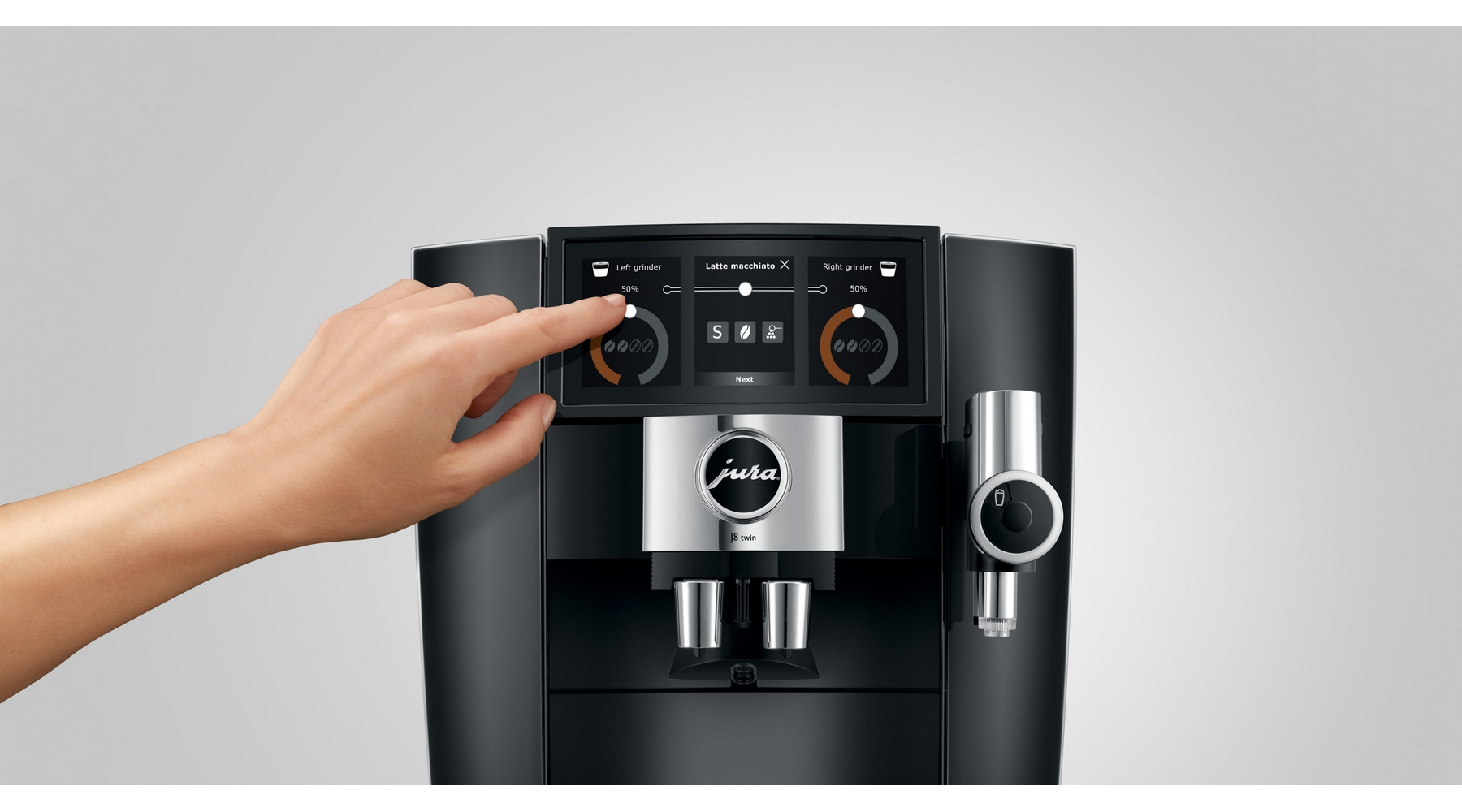 Eine Hand bedient den Touchscreen einer schwarzen Kaffeemaschine mit Jura-Logo.