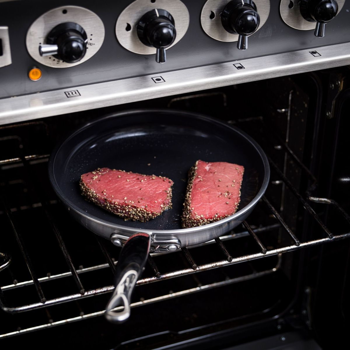 Zwei Steaks mit Pfefferkruste in einer Pfanne im Ofen auf dem Rost.