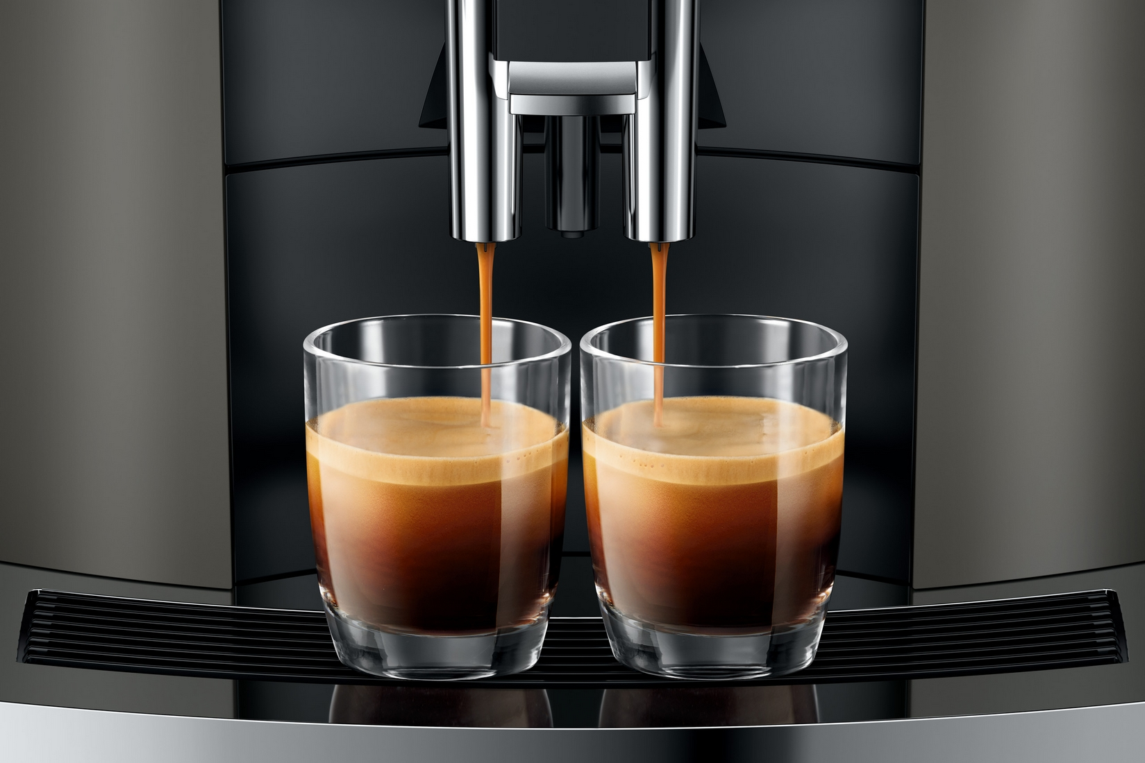 Due bicchieri vengono riempiti di espresso da una macchina da caffè.