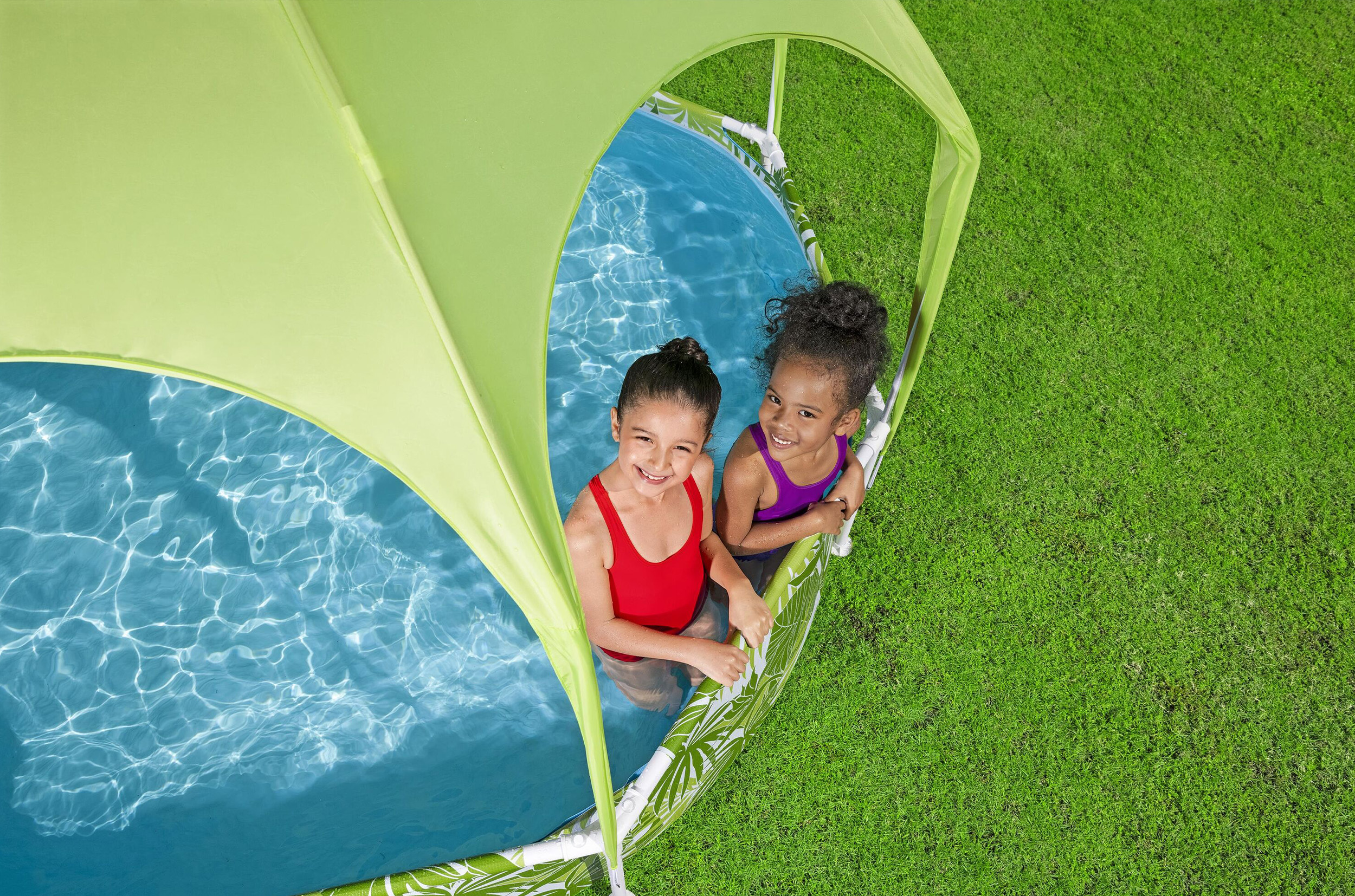 Due bambine sorridenti in una piscina per bambini con tetto verde sull'erba.