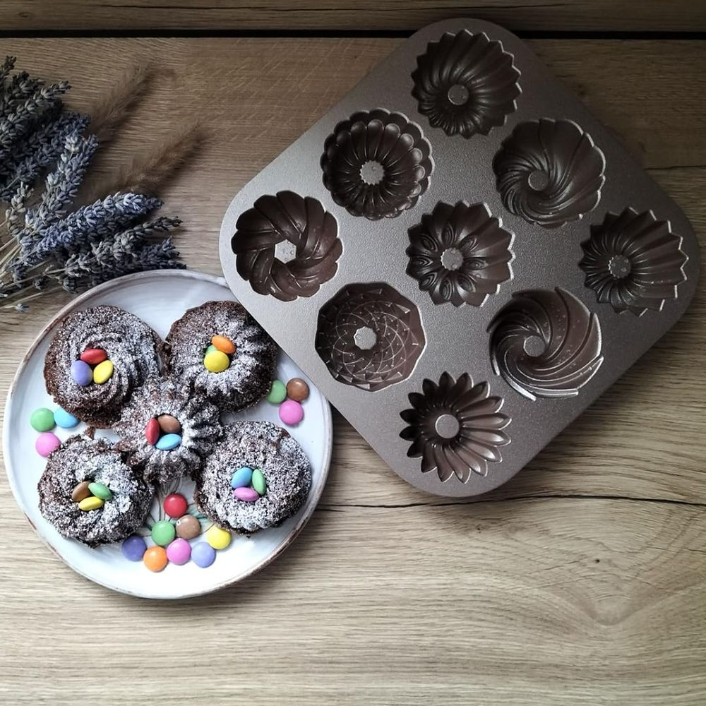 Ciastka czekoladowe oprószone cukrem pudrem i kolorowymi cukierkami obok formy do pieczenia.
