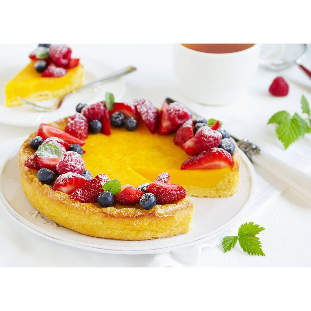 Okrągła tarta cytrynowa z dodatkiem świeżych jagód i posypana cukrem pudrem.