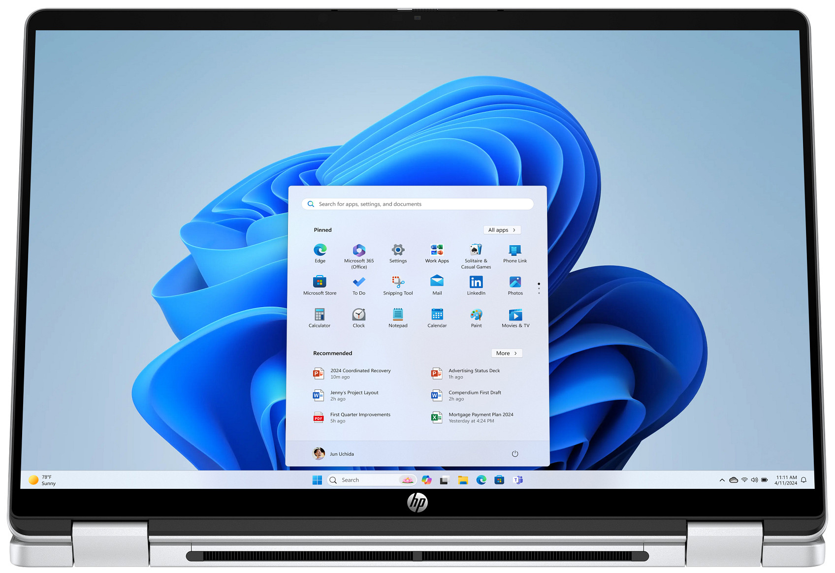 Ein Laptop mit Windows 11 Startmenü und blauer Wellen-Hintergrundgrafik.
