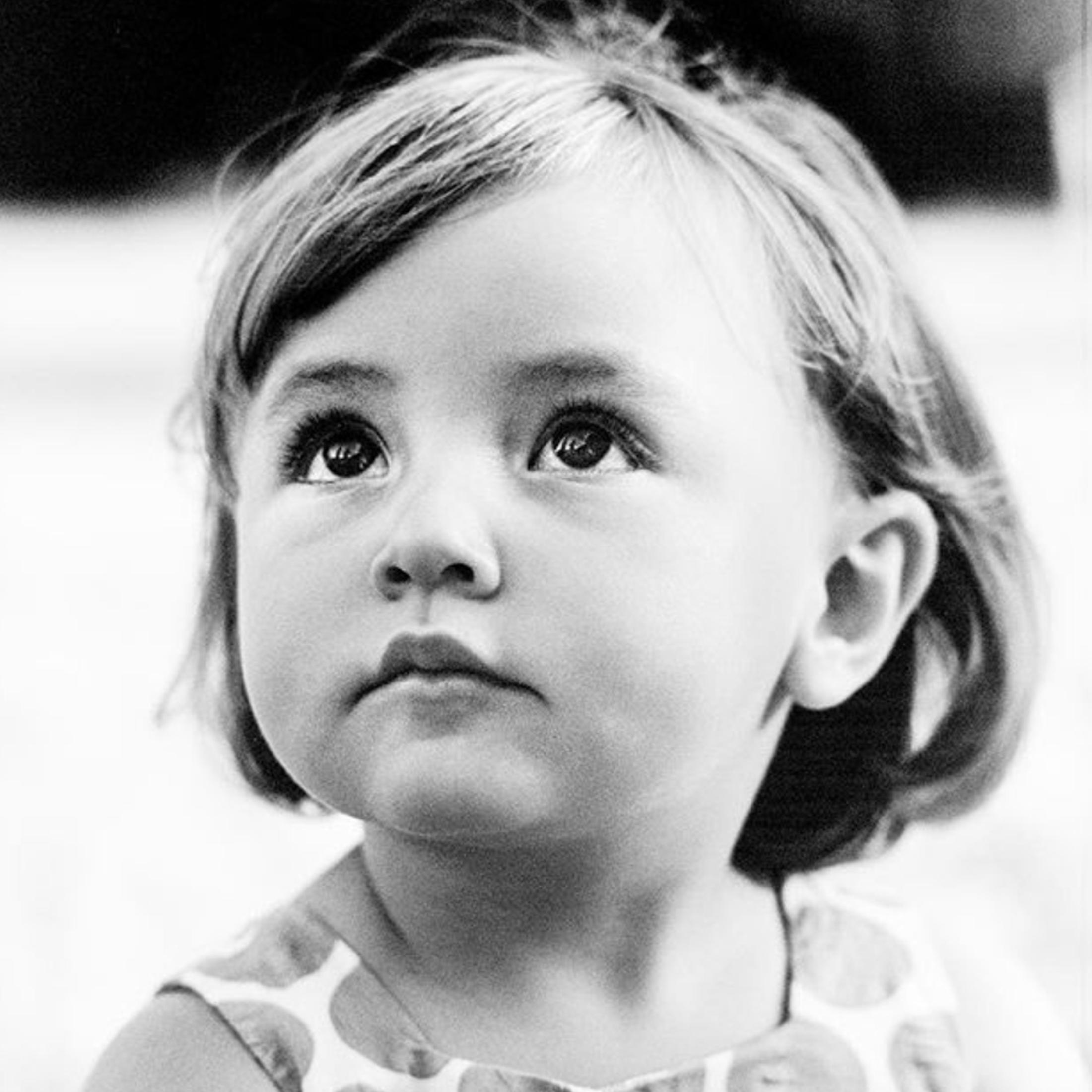 Un retrato en blanco y negro de un niño pequeño mirando hacia arriba.