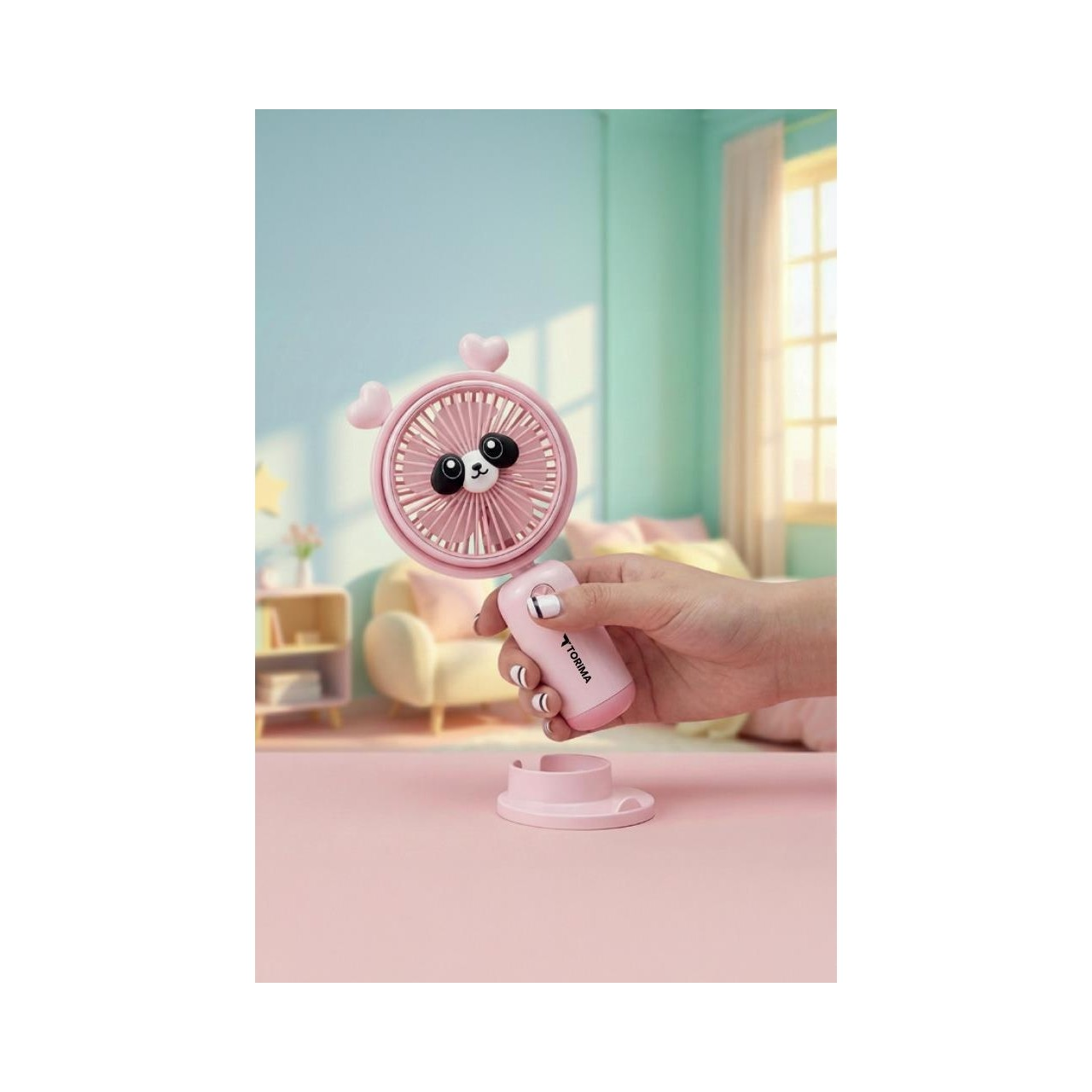 Kalpli pembe panda fan, bir el tarafından tutuluyor, arkada oda var.